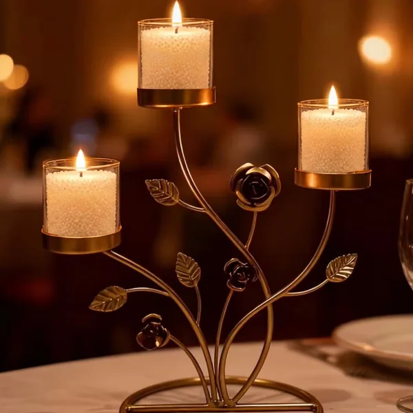 Three jars of ivory sand wax glowing in a gold rose stand on a dinner table