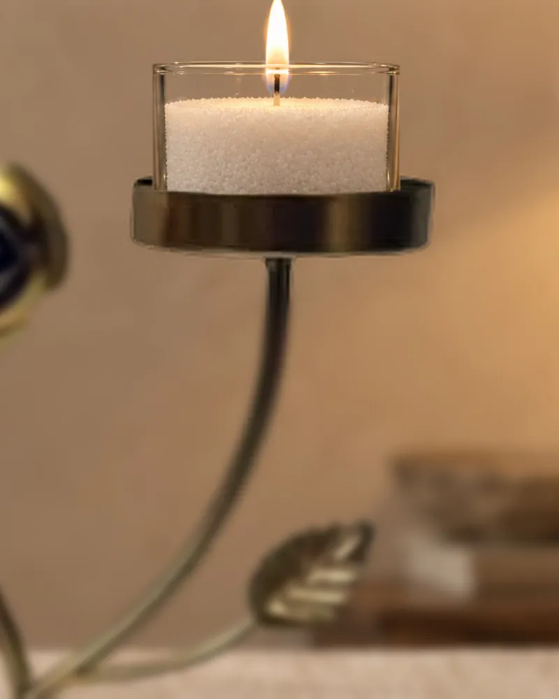 A lit candle in a gold rose stand
